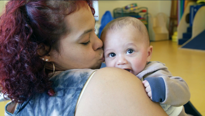 Mother holding her baby and kissing him on the cheek