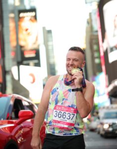 Male marathoner biting his medal in NYC